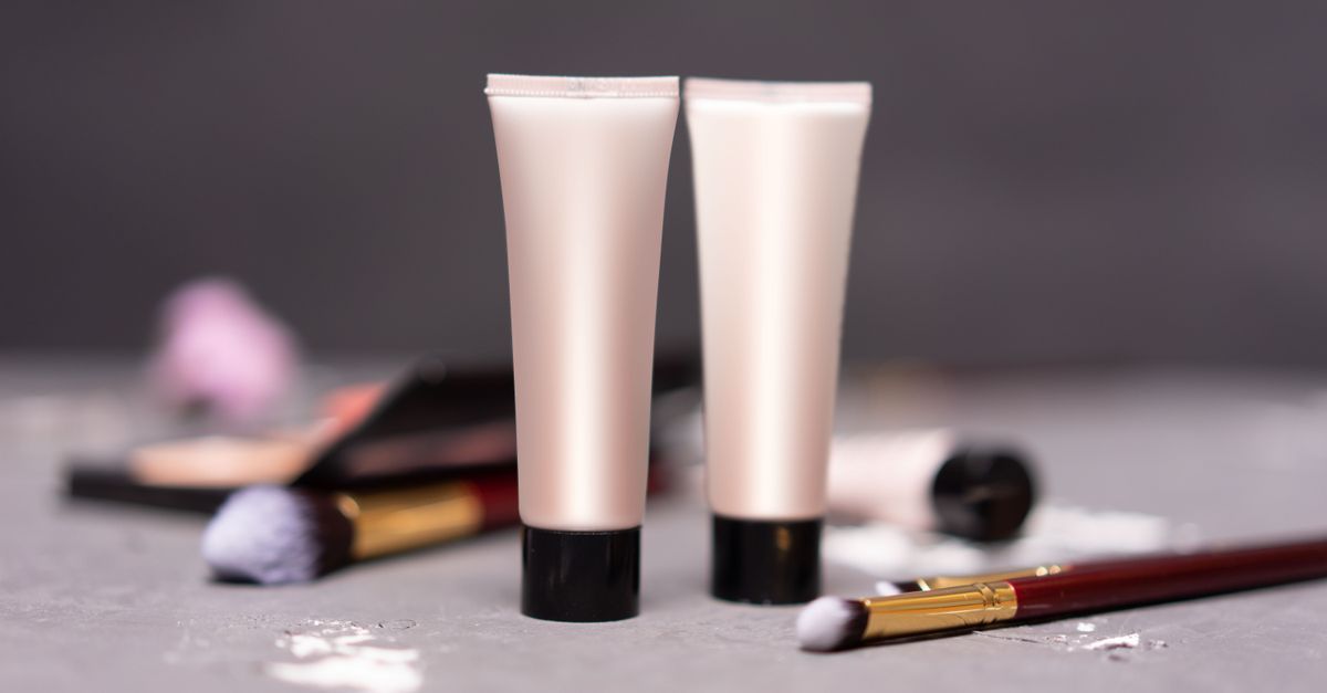 Close-up of skincare tubes with makeup brushes on a table, symbolizing beauty and self-care.